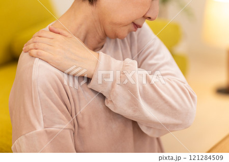 冬の夜のリビングで肩こりに苦しむミドル〜シニア女性 冬の夜のリビングで肩こりに苦しむミドル〜シニア女性 121284509