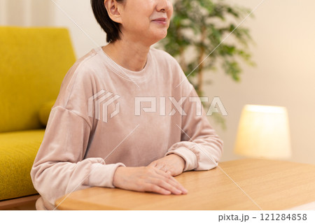 冬の夜のリビングで微笑むパジャマ姿のミドル〜シニア女性 冬の夜のリビングで微笑むパジャマ姿のミドル〜シニア女性 121284858