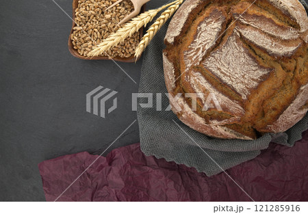 Bread loaf and wheat grain on a gray kitchen towel Bread loaf and wheat grain on a gray kitchen towel 121285916