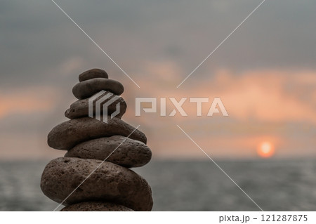 Stones Stack Sunset Beach - A Zen rock cairn balances precariously against a picturesque sunset over the ocean. Stones Stack Sunset Beach - A Zen rock cairn balances precariously against a picturesque sunset over the ocean. 121287875