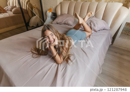 A girl is laying on a bed with her head on her hand. She is looking up at the ceiling. A girl is laying on a bed with her head on her hand. She is looking up at the ceiling. 121287948
