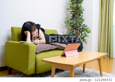 リビングでタブレットの動画を見る若い女性 動画視聴 ライブ実況 中継 寝転ぶ リビングでタブレットの動画を見る若い女性 動画視聴 ライブ実況 中継 寝転ぶ 121290331