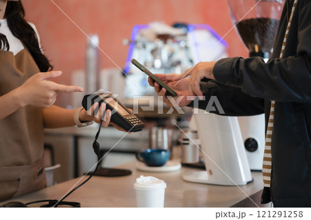 Closeup shot of cashier hands. Seller using touch smartphone for accepting client customer payment. Small business of coffee shop. 121291258