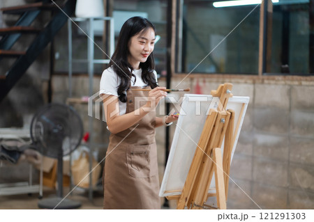 Young female artist painting on canvas in the home studio, fine arts and creativity concept. Young female artist painting on canvas in the home studio, fine arts and creativity concept. 121291303