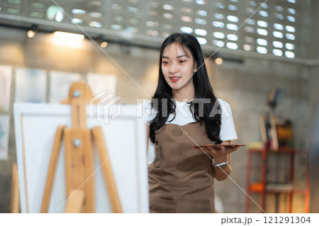 Young female artist painting on canvas in the home studio, fine arts and creativity concept. Young female artist painting on canvas in the home studio, fine arts and creativity concept. 121291304