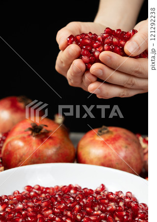 Handful of pomegranate seeds, pomegranate seeds in hands, black background Handful of pomegranate seeds, pomegranate seeds in hands, black background 121292238