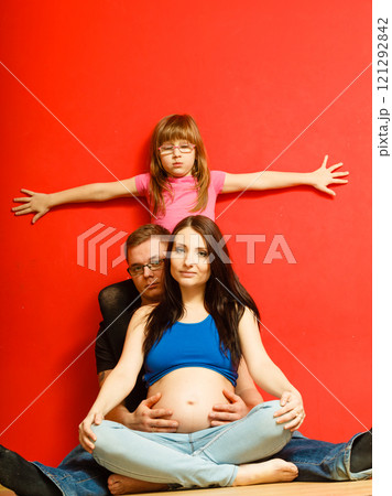 Pregnant woman, man and daughter posing. 121292842