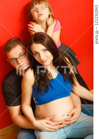 Pregnant woman, man and daughter posing. 121292843