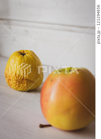Fresh and rotten apple on white background. Fresh red apple and wrinkled apple. Young and old concept. Aging process concept. Skin care concept. Decay in nature. Difference in age. Passing of time 121294656