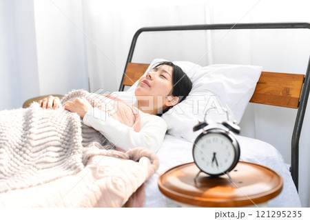 心地良くベッドで寝るアジア人の若い女性 心地良くベッドで寝るアジア人の若い女性 121295235