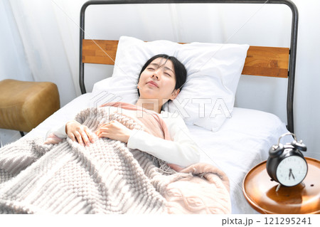 心地良くベッドで寝るアジア人の若い女性 121295241