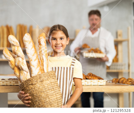 Girl daddy assistant poses in bakery with baguettes of bread 121295328