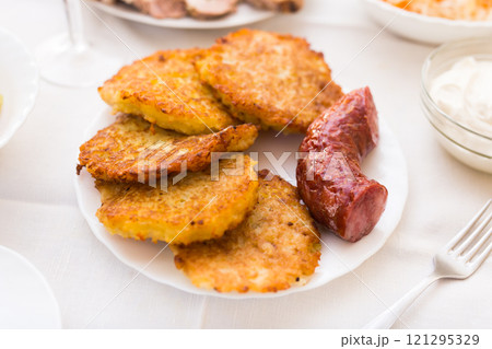Potato pancakes with fried sausage on white plate 121295329