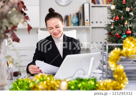 Woman working in workplace in Christmas decorated office 121295332