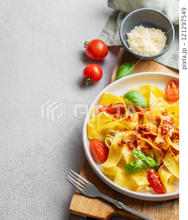 Tagliatelle pasta with tomato sauce, basil and parmesan cheese in a plate on a wooden board Tagliatelle pasta with tomato sauce, basil and parmesan cheese in a plate on a wooden board 121297549