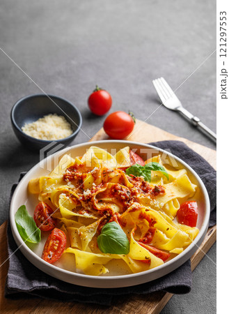 Tagliatelle pasta with tomato sauce, basil and parmesan cheese in a plate on a wooden board Tagliatelle pasta with tomato sauce, basil and parmesan cheese in a plate on a wooden board 121297553