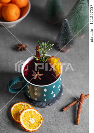Mulled wine with orange, cinnamon and rosemary in a cup on a dark background with tangerines and fir Mulled wine with orange, cinnamon and rosemary in a cup on a dark background with tangerines and fir 121297557