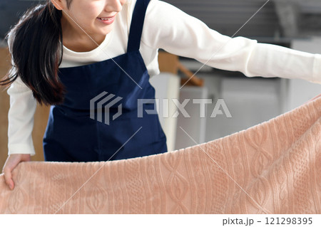 ベッドメイキングをするエプロン姿の女性 121298395