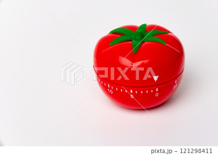 Close up view of mechanical tomato shaped kitchen clock timer for cooking and studying. Used for pomodoro technique for time & productivity management. Isolated on white background, set at 5 minutes. 121298411