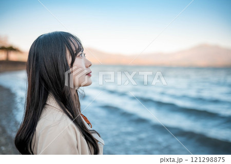 青空と湖とトレンチコートの若い女性 121298875