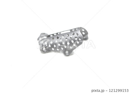 Titanium dental membranes for directed bone regeneration printed on 3D printer isolated on white background. Membrane for lower jaw printed from biocompatible titanium powder. Implants and prostheses 121299153