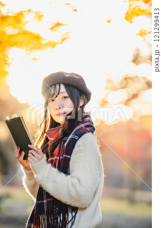 読書の秋　紅葉している公園で読書をする若い女性 121299413
