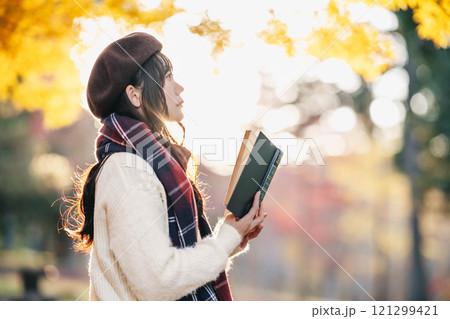 読書の秋　紅葉している公園で読書をする若い女性 121299421