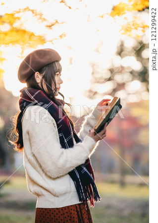 読書の秋　紅葉している公園で読書をする若い女性 121299422