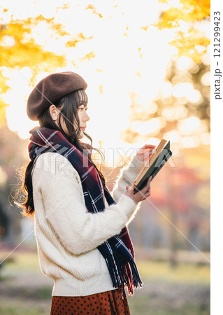 読書の秋　紅葉している公園で読書をする若い女性 121299423