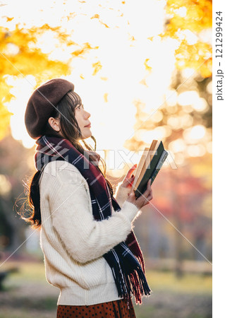 読書の秋　紅葉している公園で読書をする若い女性 121299424