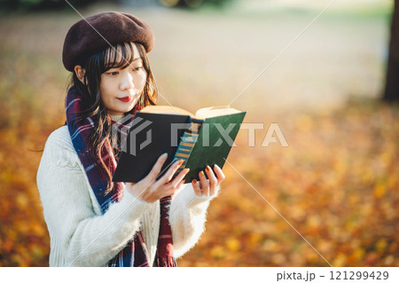 読書の秋　紅葉している公園で読書をする若い女性 121299429