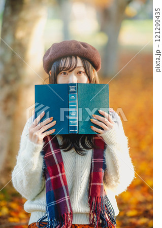 読書の秋　紅葉している公園で読書をする若い女性 121299435