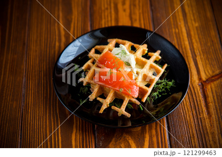 vegetable potato waffles with spread and lightly salted red fish, in a plate on a wooden table 121299463
