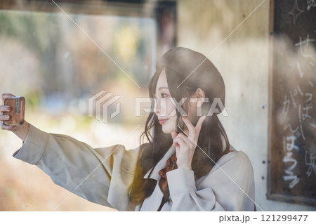 バス停で旅行の写真を撮る若い女性　撮影協力・羽後交通 121299477