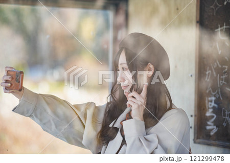 バス停で旅行の写真を撮る若い女性　撮影協力・羽後交通 121299478