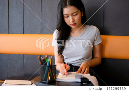 Young woman engages in note-taking at workspace. 121299589