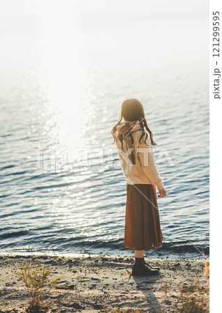 湖と夕陽　マフラーをした若い女性 121299595