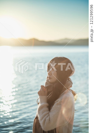 湖と夕陽　マフラーをした若い女性 121299596