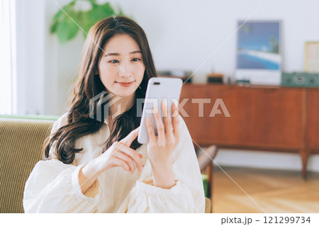 ソファに座ってスマホを見る女性 ソファに座ってスマホを見る女性 121299734