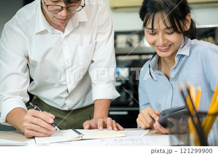 Engineers looking and discussing over blueprints on desk. 121299900