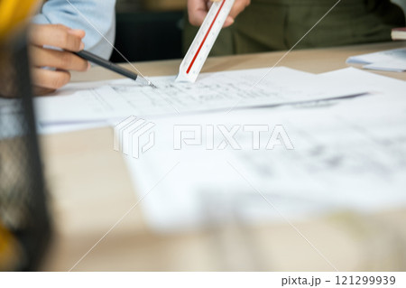 Engineers pointing and discussing over blueprints on desk. Engineers pointing and discussing over blueprints on desk. 121299939