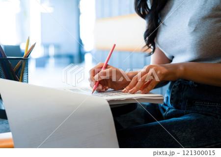 Young woman engages in note-taking at workspace. Young woman engages in note-taking at workspace. 121300015