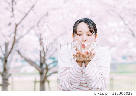 桜の花びらを吹く若い女性 121300025