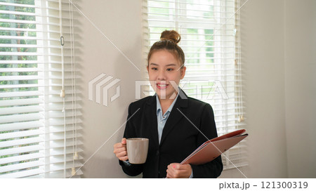 Businesswoman sitting at desk on couch in workplace or at home working on laptop and analyzing data on charts and graphs and writing on papers to make business plan and strategies for company, 121300319