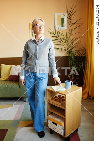 Full length shot of stylish mature woman wearing smart casual outfit confidently posing for photo in modern cozy office with beige walls 121301284