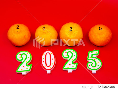 Four oranges and 2025shaped candles on a red background Four oranges and 2025shaped candles on a red background 121302300