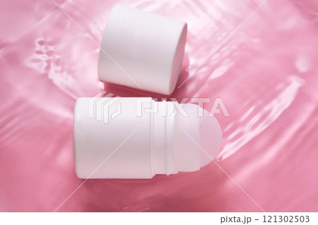 Roll-on deodorant on a pink background in water. 121302503