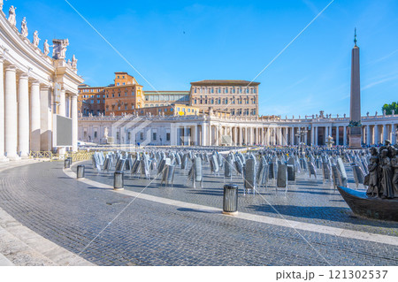 Saint Peter's Square features its magnificent architecture, elaborate fountains, and towering obelisk under a clear blue sky. The square is arranged for visitors and visitors await their turn. Saint Peter's Square features its magnificent architecture, elaborate fountains, and towering obelisk under a clear blue sky. The square is arranged for visitors and visitors await their turn. 121302537