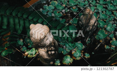 A statue of a woman is surrounded by vibrant green plants A statue of a woman is surrounded by vibrant green plants 121302787