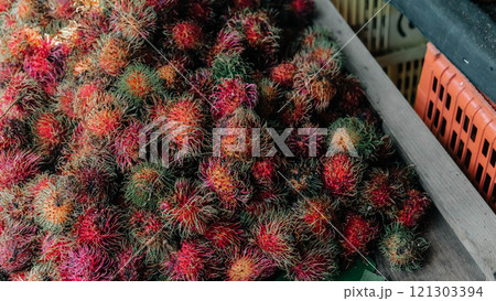 A vibrant display of colorful rambutans showcased prominently in a lively marketplace setting 121303394